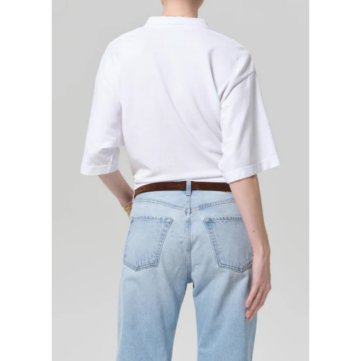 Person wearing a white t-shirt and light blue jeans on a plain background
