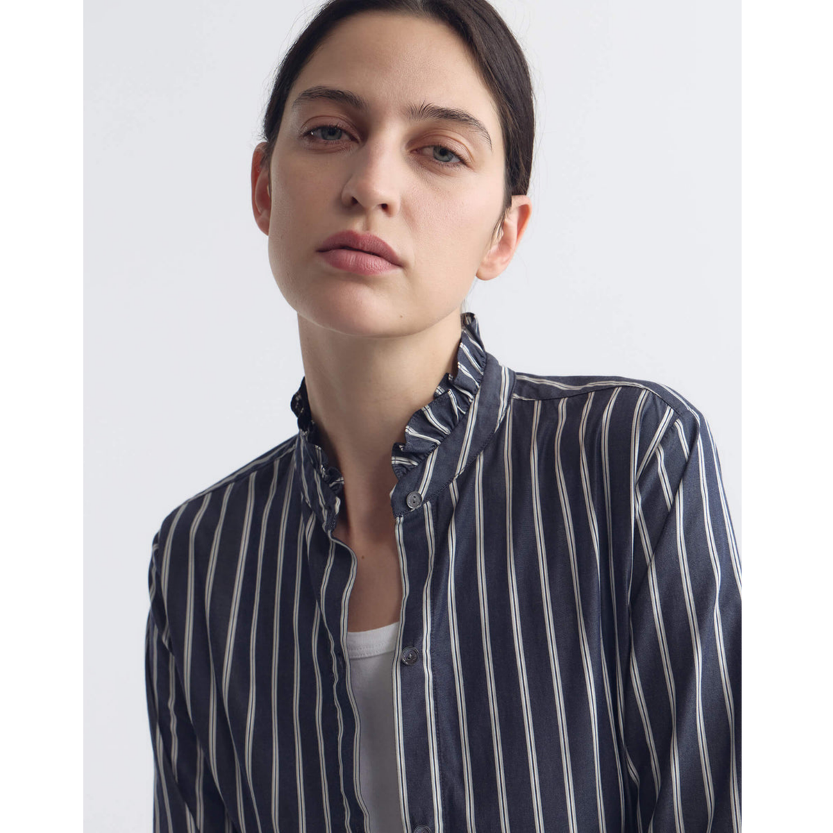 Woman wearing a navy and white striped shirt against a plain background