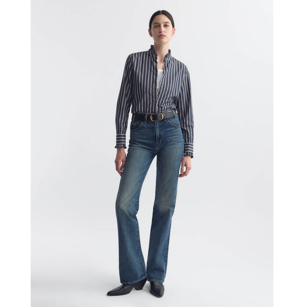 Woman wearing a striped shirt and blue jeans on a white background