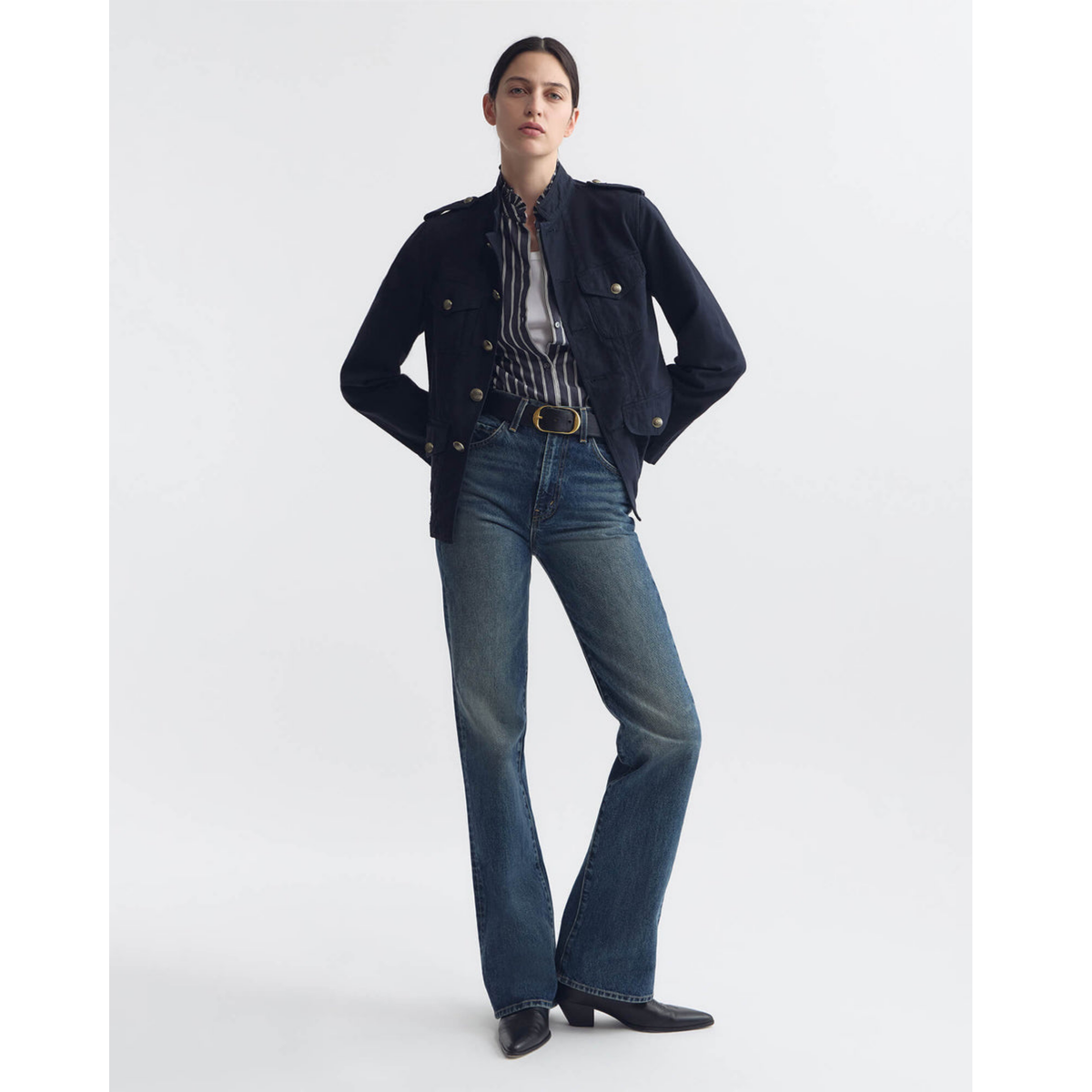 Woman wearing a dark denim jacket and jeans on a white background