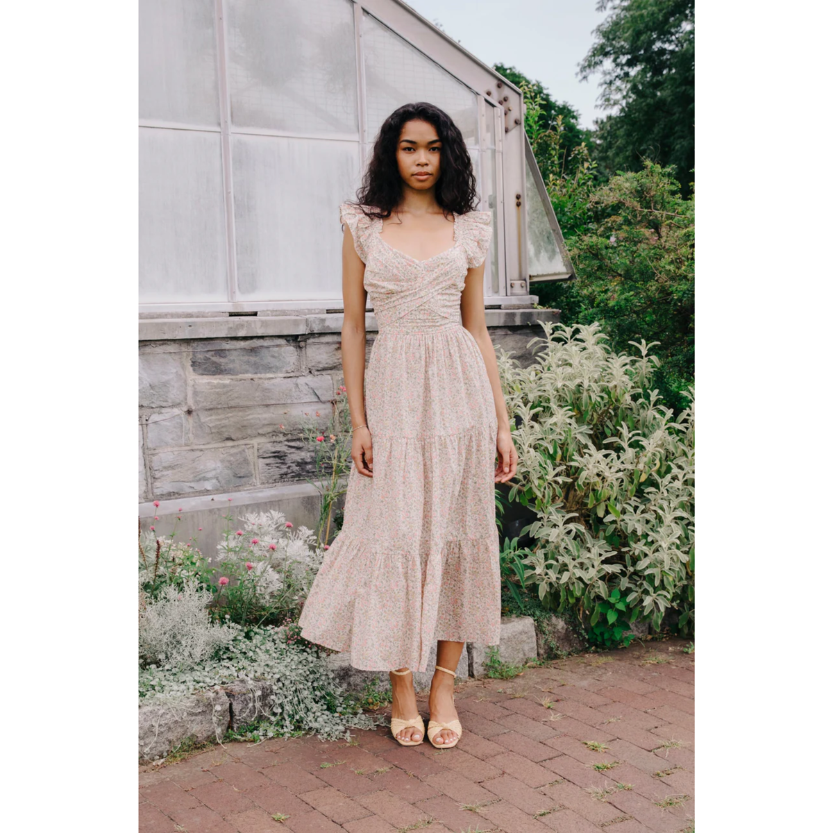 Woman in a beige dress standing in a garden setting