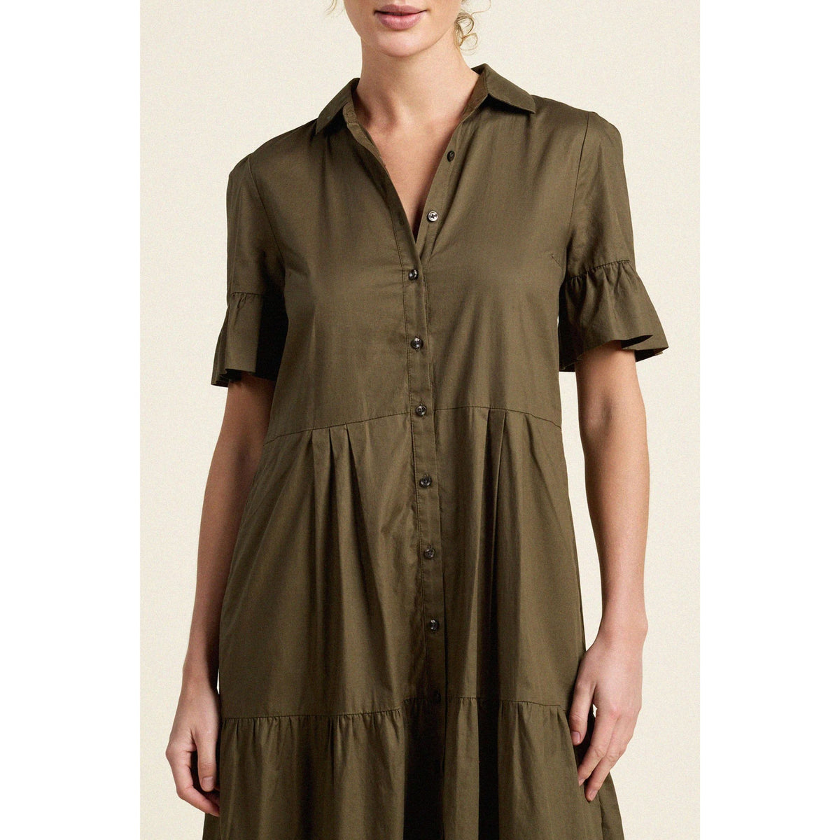 An olive green short-sleeve button-down dress with ruffled sleeves, worn by a model against a light beige background.