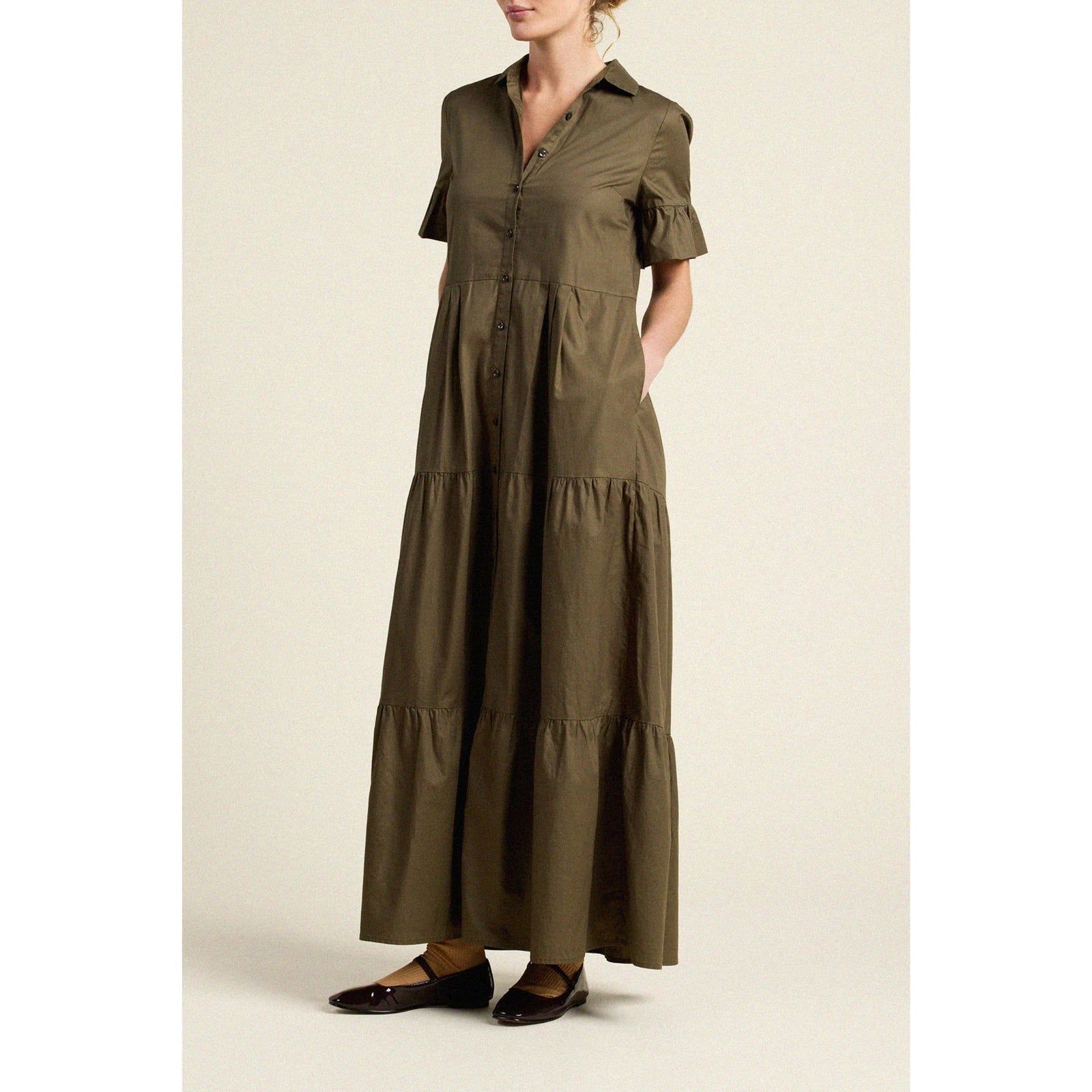 An olive brown short-sleeve midi dress with ruffled sleeves, a button-down front, and a pink floral waist tie belt, shown against a solid light beige background.