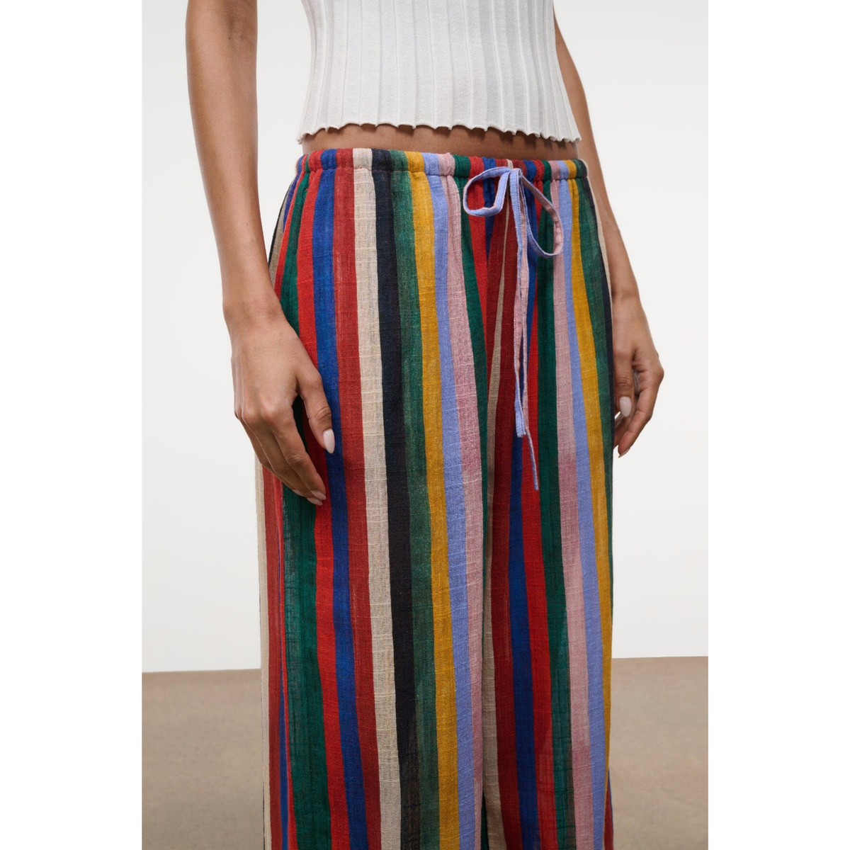Multicolored striped pants worn by a person on a white background