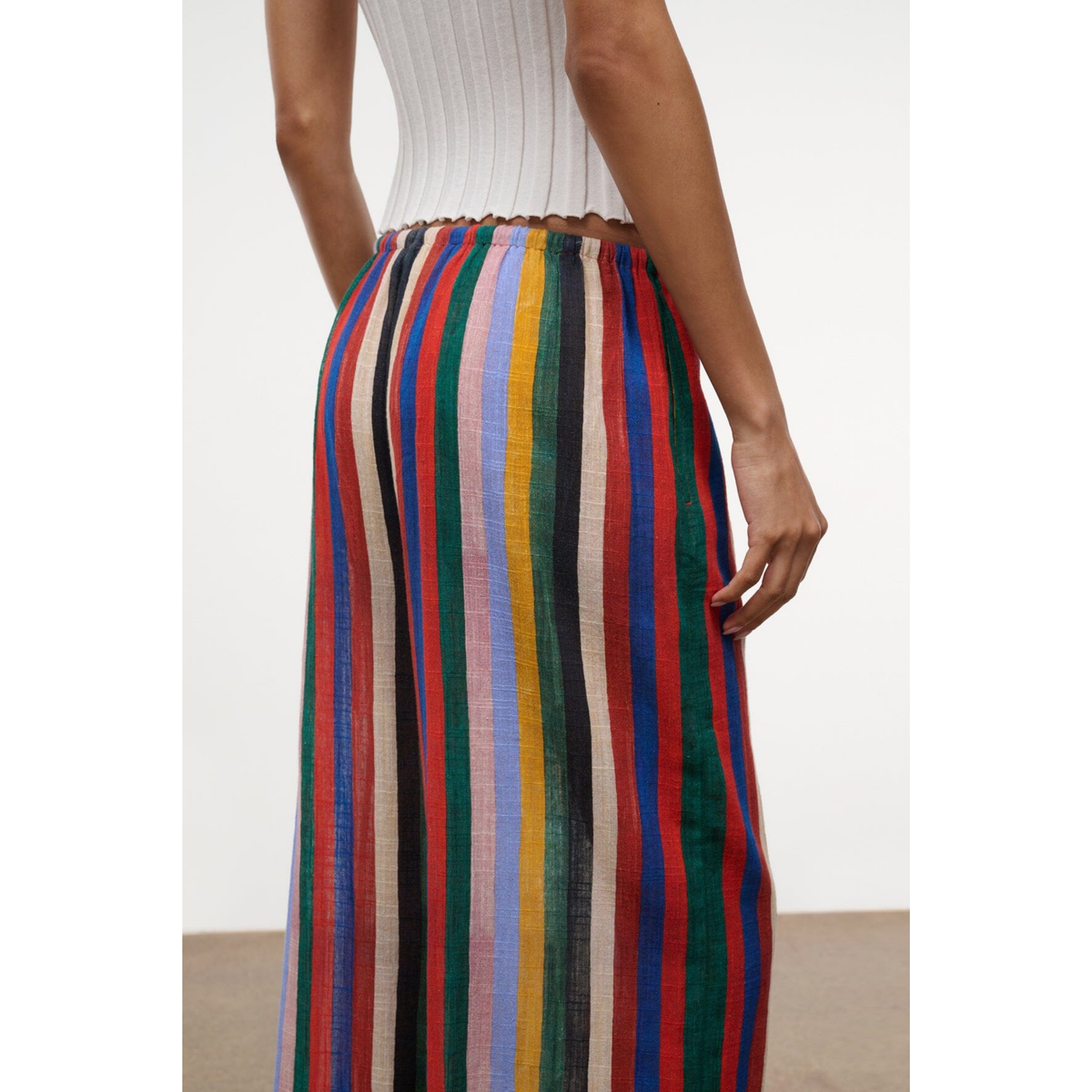 Multicolored striped pants worn by a person on a white background