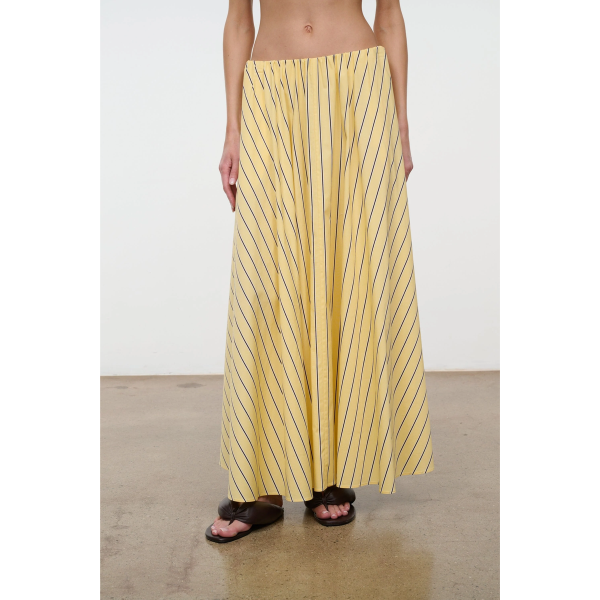 Person wearing a yellow striped skirt on a plain background