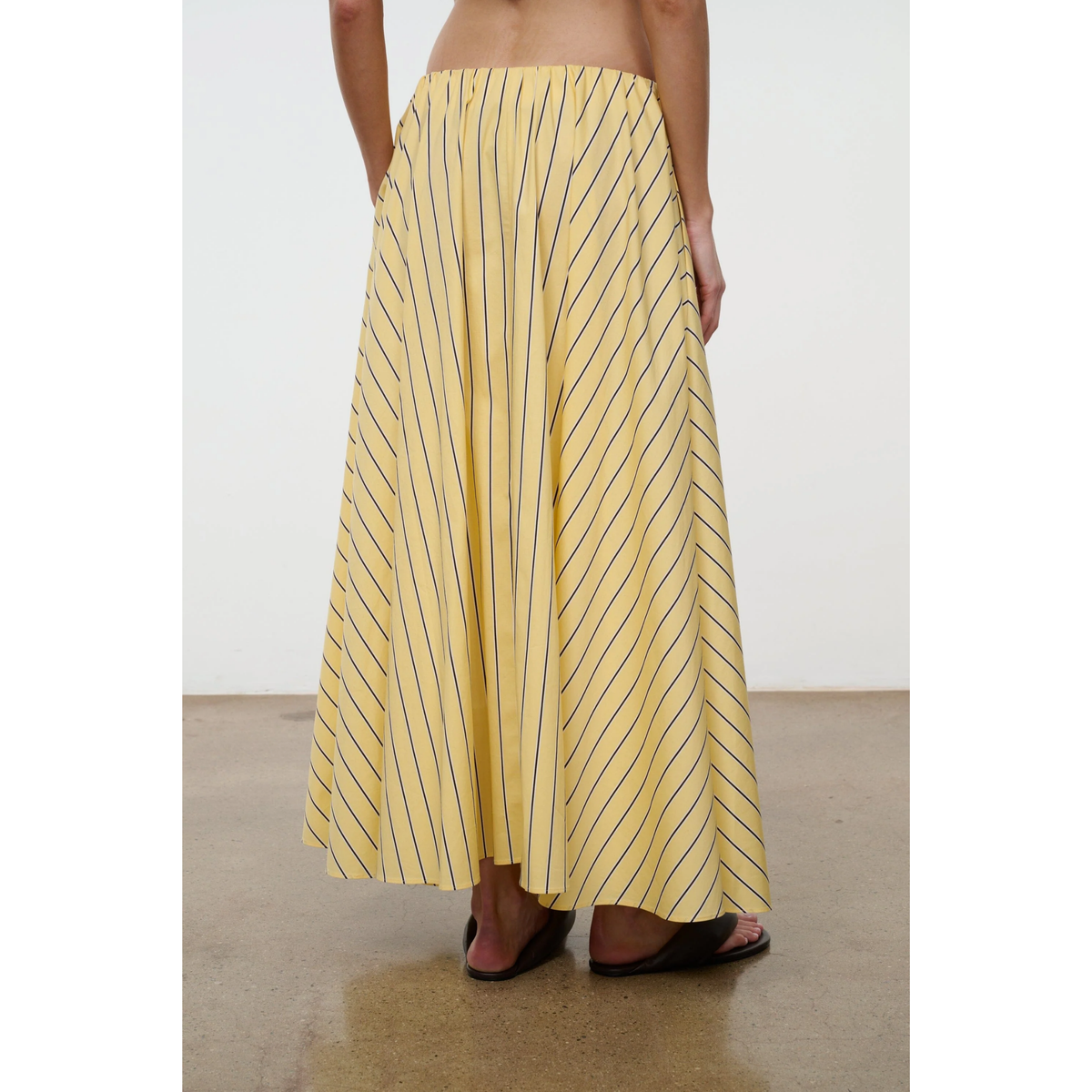 Yellow striped skirt worn by a person on a plain background
