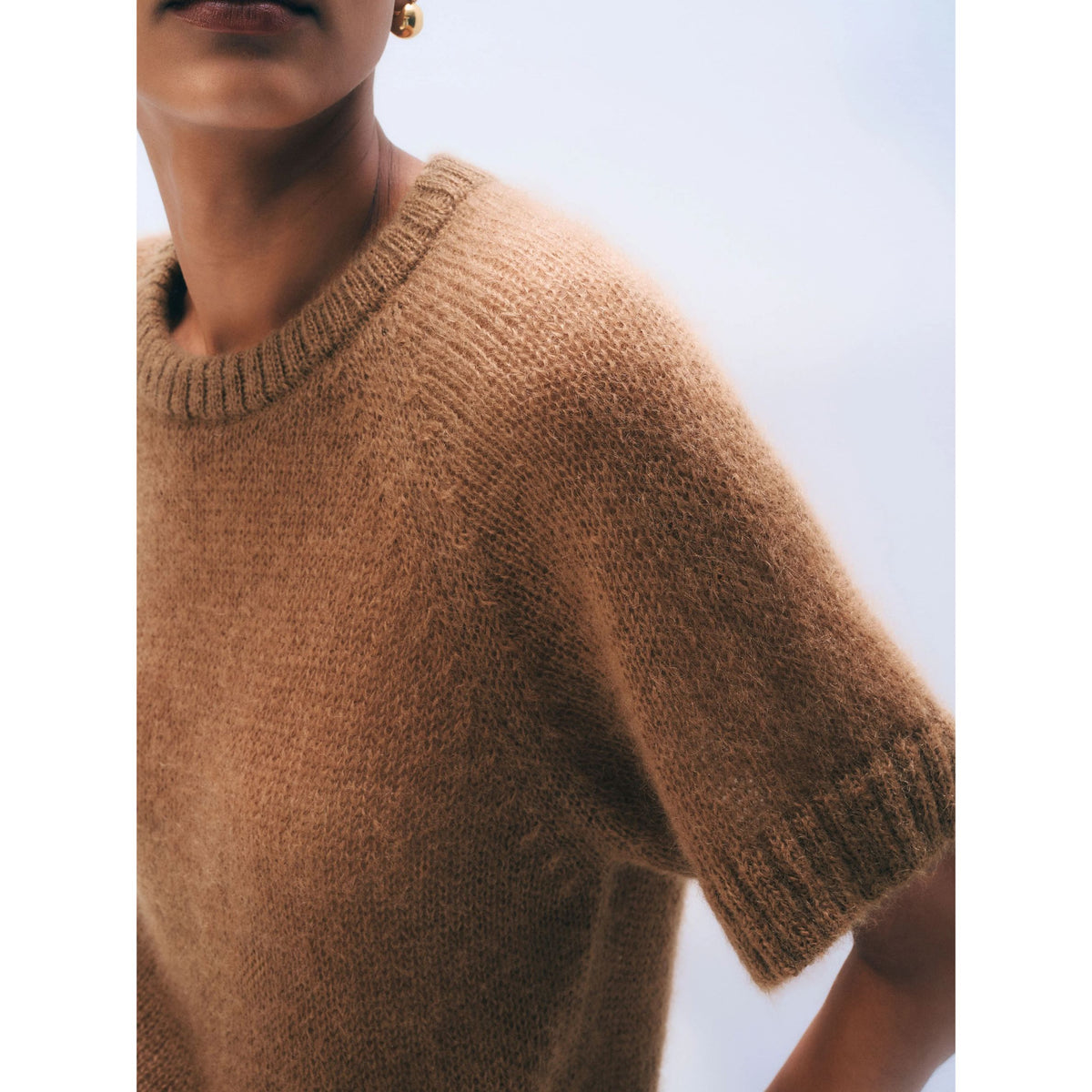 Close-up shot showing the ribbed crew collar, raglan shoulder seam detail, and textured knit surface of the Camel brown mohair blend tee.