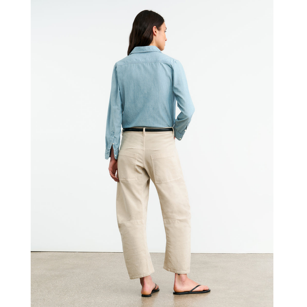 Person wearing a light blue shirt and beige pants on a plain background
