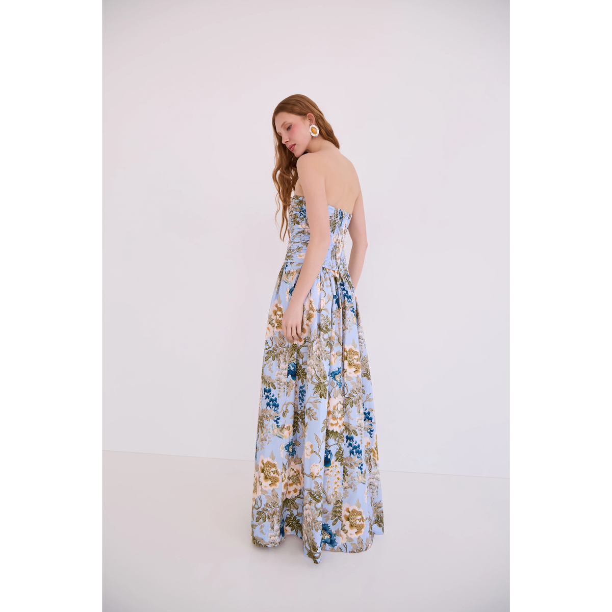 Woman wearing a floral strapless dress against a white background