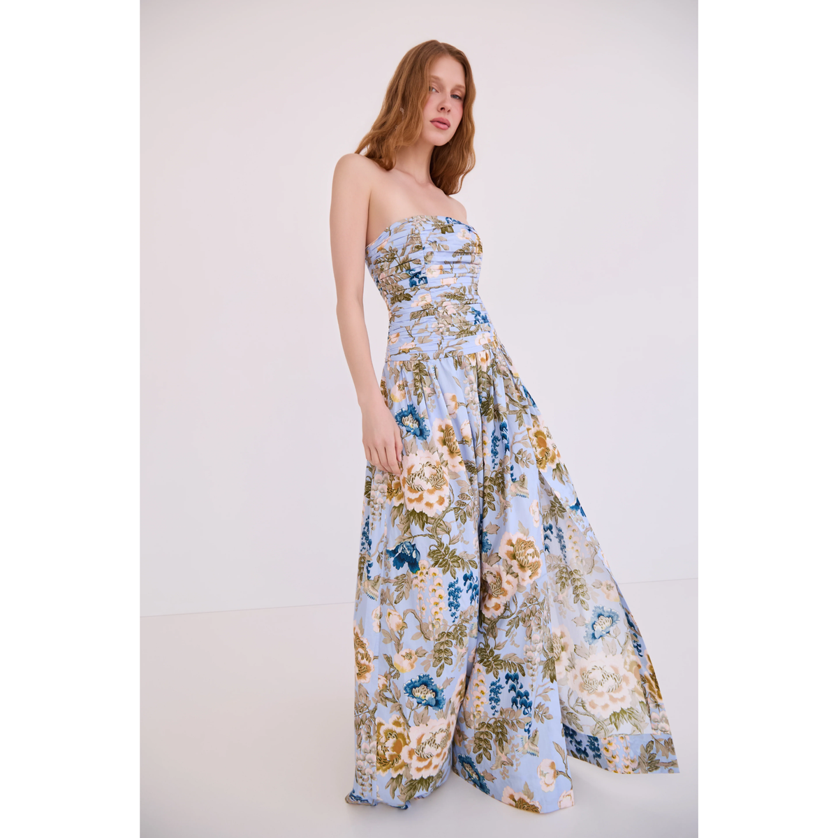 Woman wearing a strapless floral dress against a white background