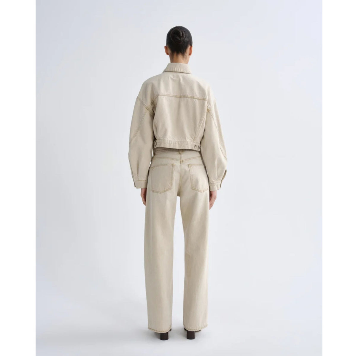 Full-length back view of a model with hair in a bun wearing the AGOLDE Palmer Jacket in Arena and matching khaki pants against a light gray background.