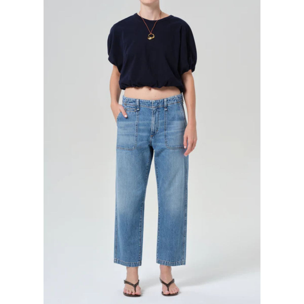 Person wearing a navy top and light blue jeans on a white background