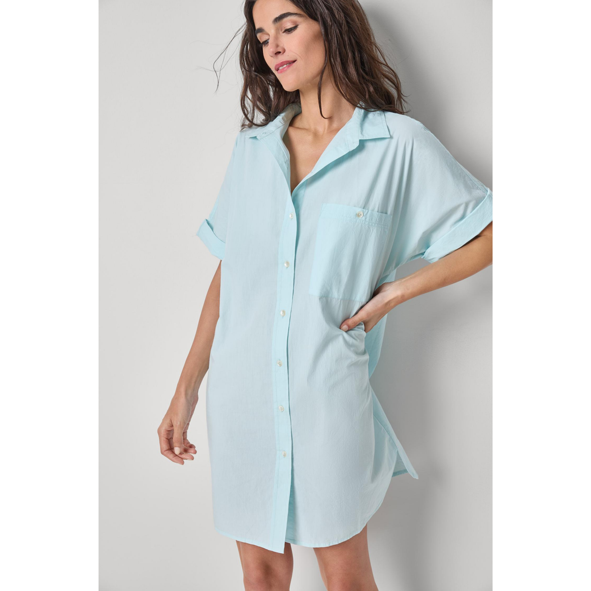 Woman wearing a light blue shirt dress against a plain background