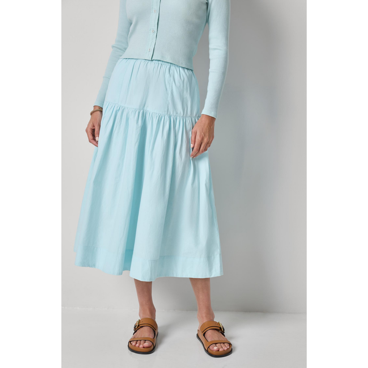 Person wearing a light blue dress with a plain background