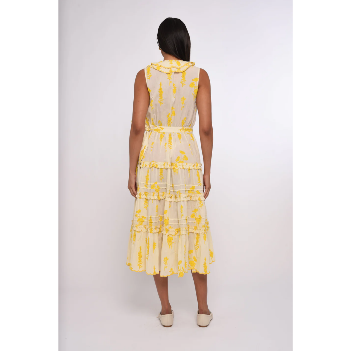 Woman wearing a yellow floral dress on a white background