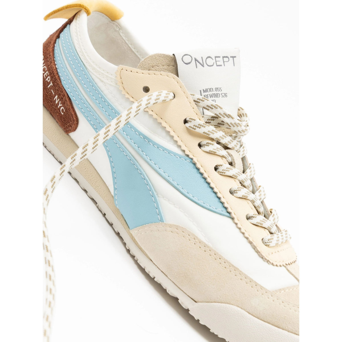 A close-up of a Oncept '90s style sneaker featuring cream suede, white leather, light blue side panels, beige rope laces, and a brown heel tab with 'ONCEPT NYC' text.