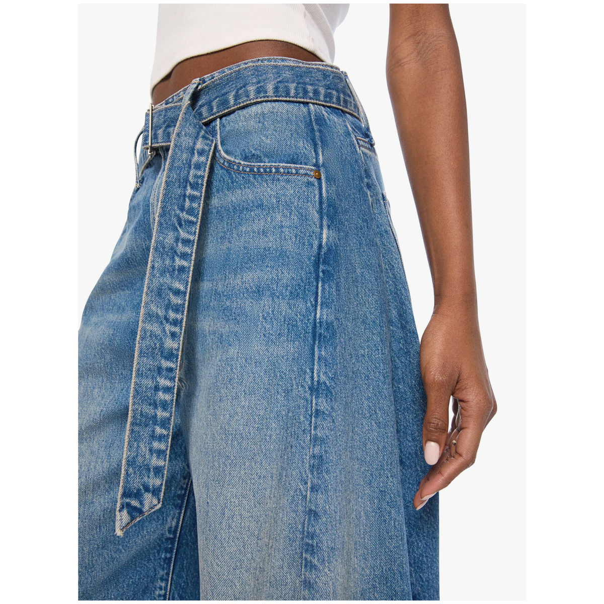 Close-up of a model wearing high-waisted wide-leg blue denim jeans with a matching tie belt, shown against a plain light background.