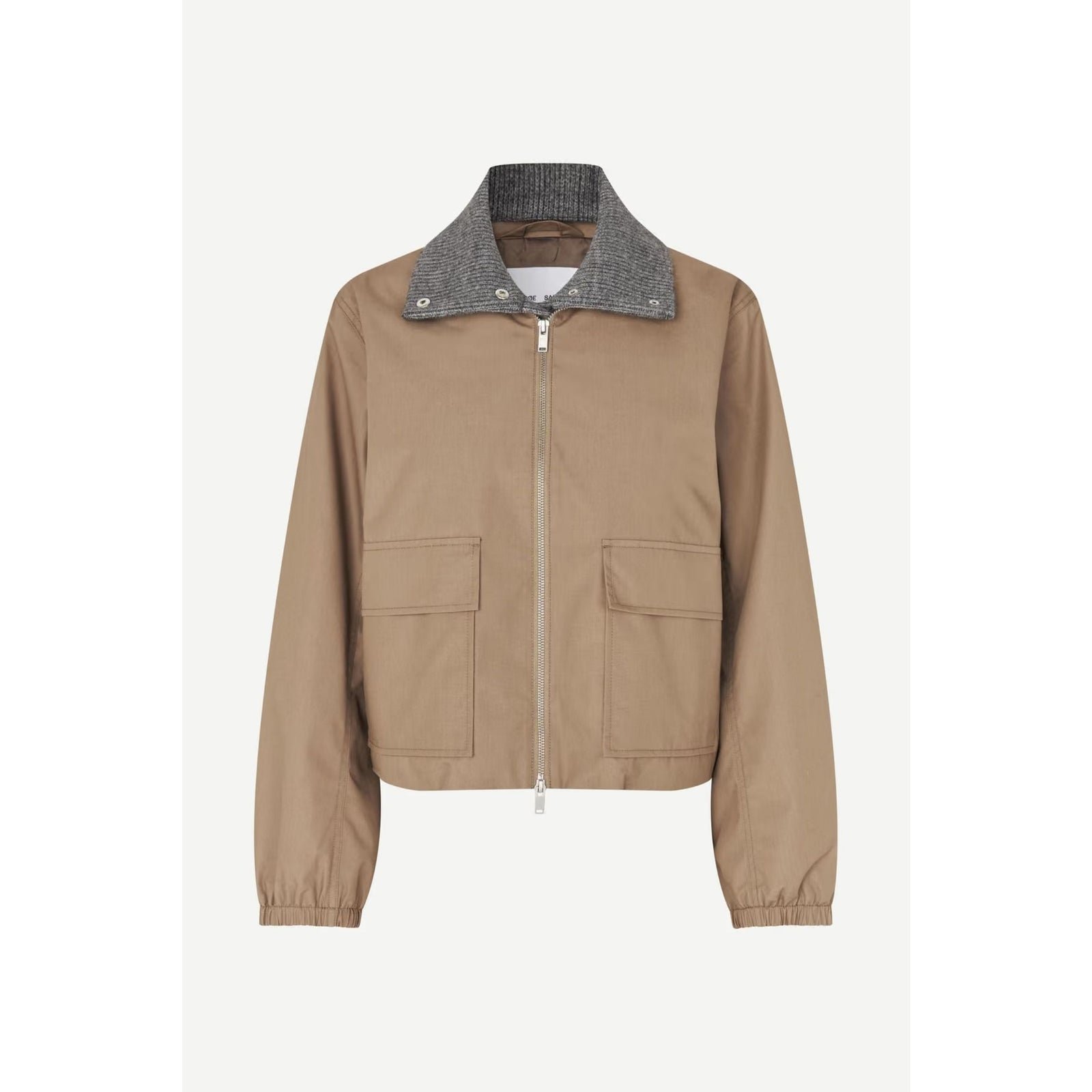 A cropped utility jacket in tan canvas with a contrasting gray textured knit collar, front zipper, and two large flap pockets, shown on a light gray background.