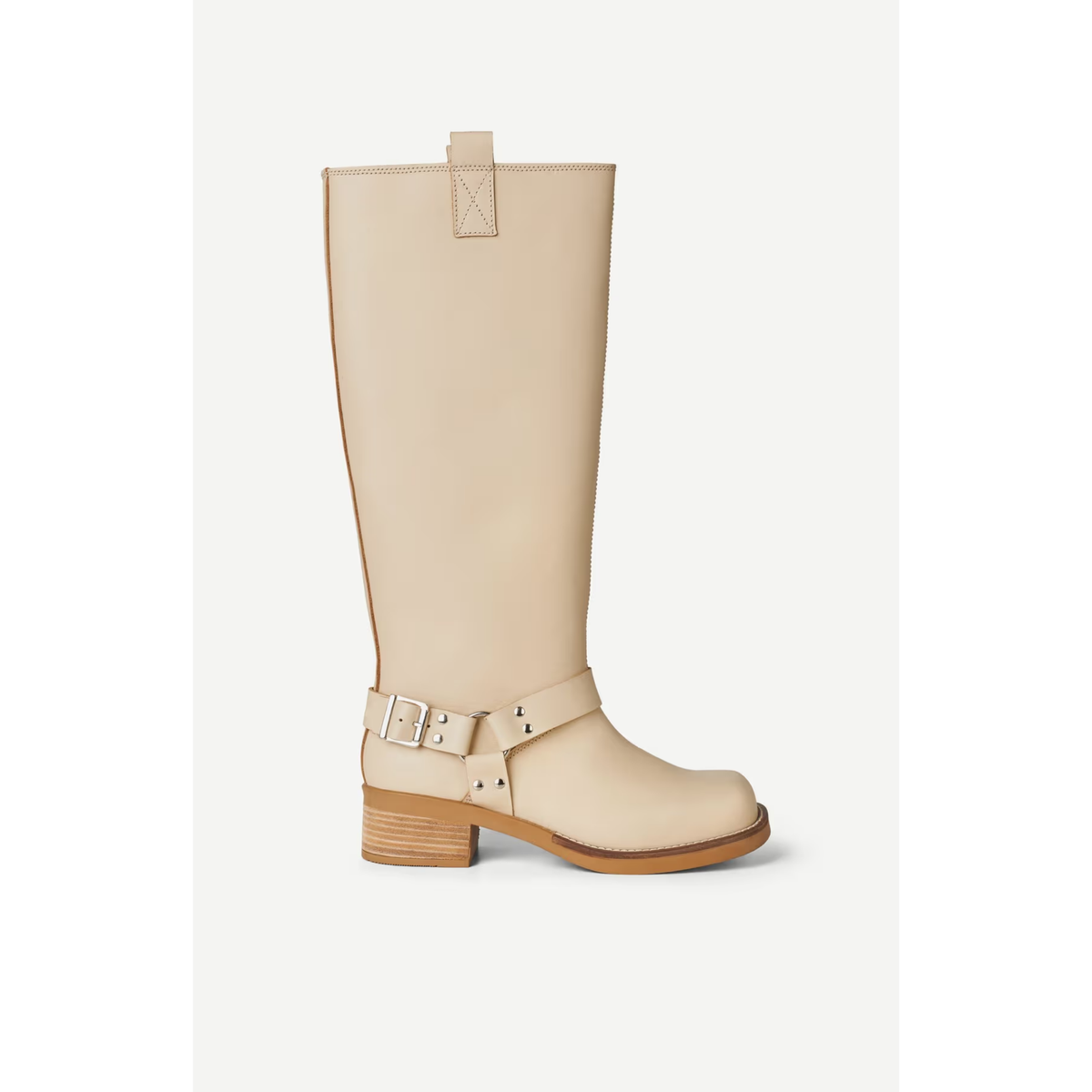 A single knee-high boot in a light beige faux leather, featuring a low block heel, a decorative buckle strap around the ankle, and a pull tab at the top, shown against a plain light background.