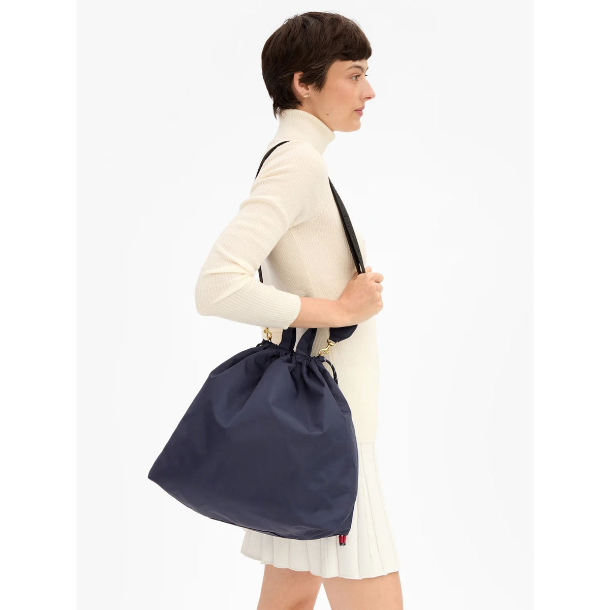 Side view of a model carrying the navy blue nylon bag over her shoulder.