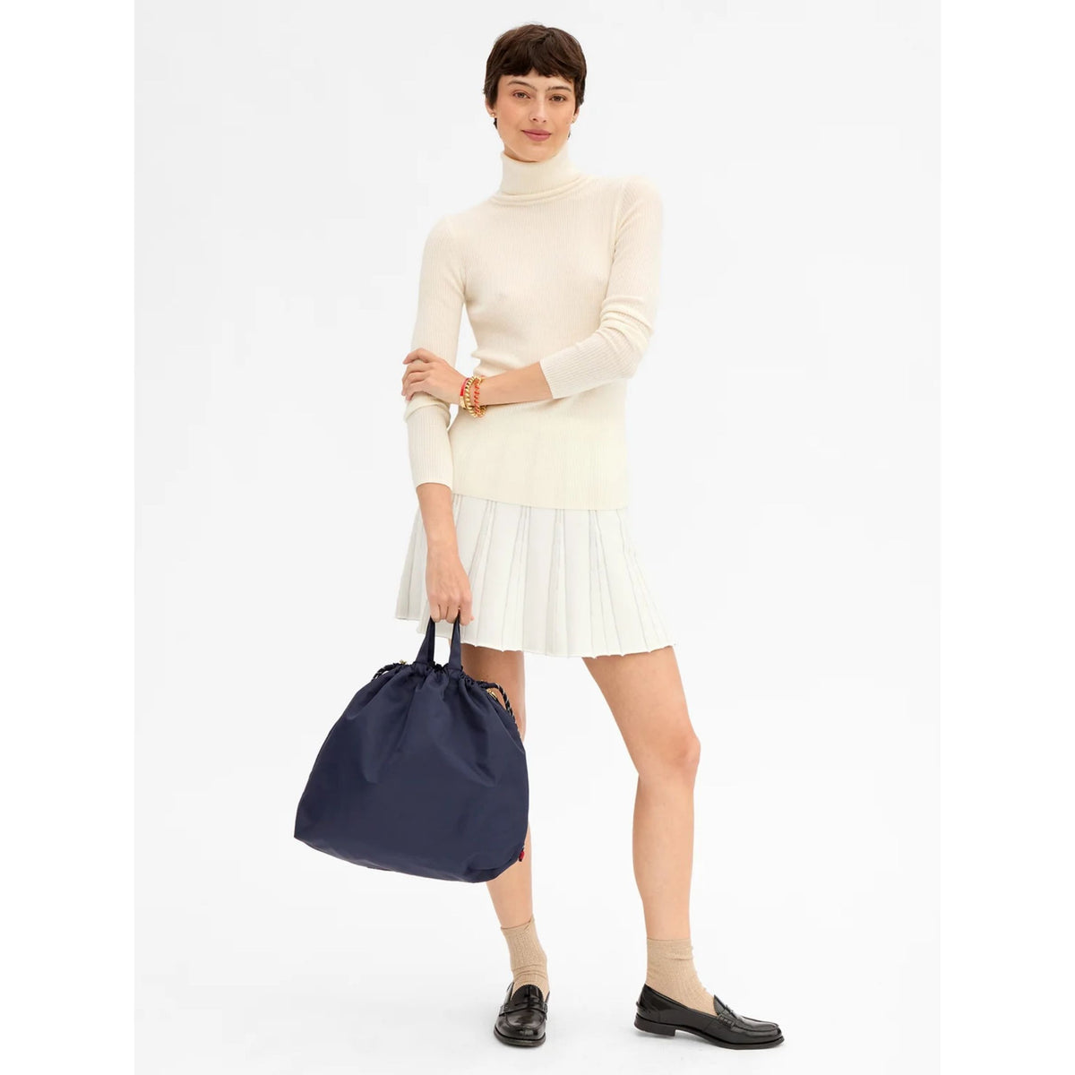 Full-length front view of a model in a light-colored outfit carrying the navy blue nylon bag by its shoulder strap.