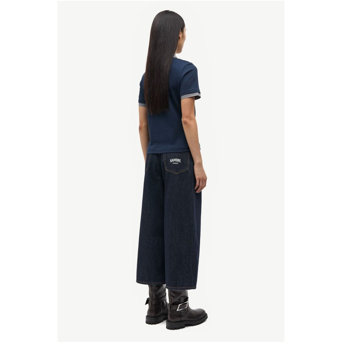A model shown from the back wearing a navy blue t-shirt with grey ribbed trim, dark wide-leg denim jeans with a visible 'Missoni' patch on the pocket, and black leather boots, against a plain off-white background.