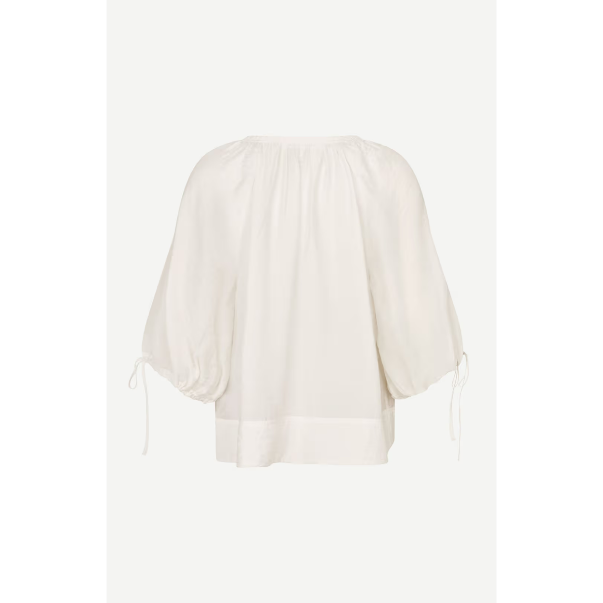 An off-white blouse with voluminous elbow-length sleeves, gathered elastic at the shoulders and cuffs, and a straight hem, shown against a light gray background.
