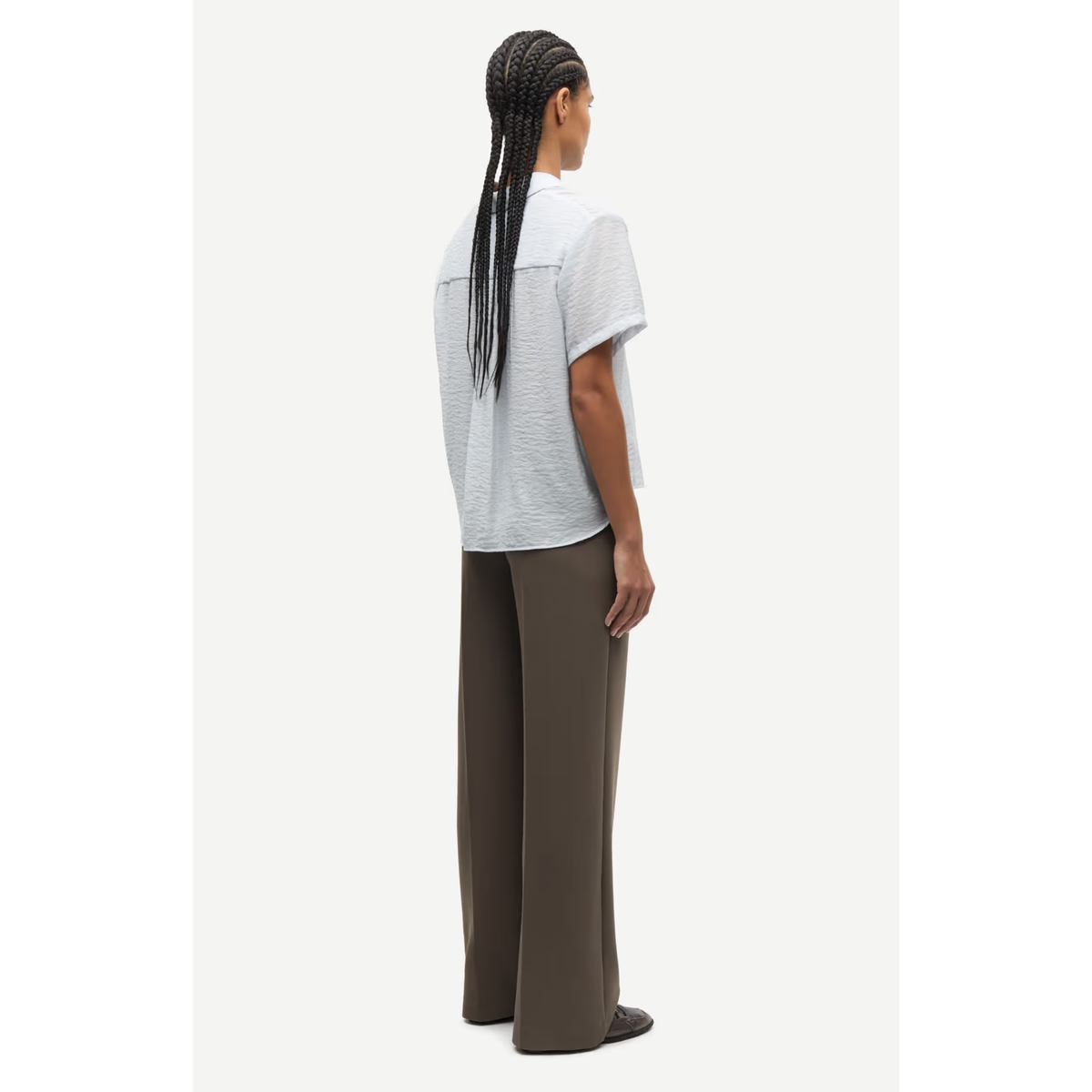 Person wearing a light gray t-shirt and brown pants on a white background