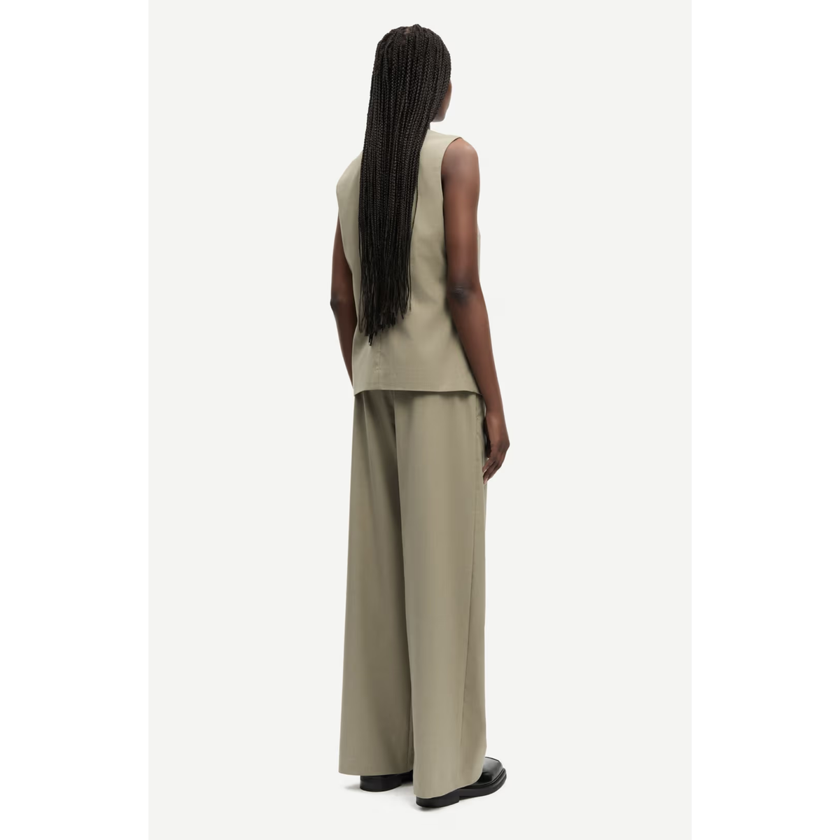 Woman wearing a beige sleeveless top and wide-leg pants on a white background