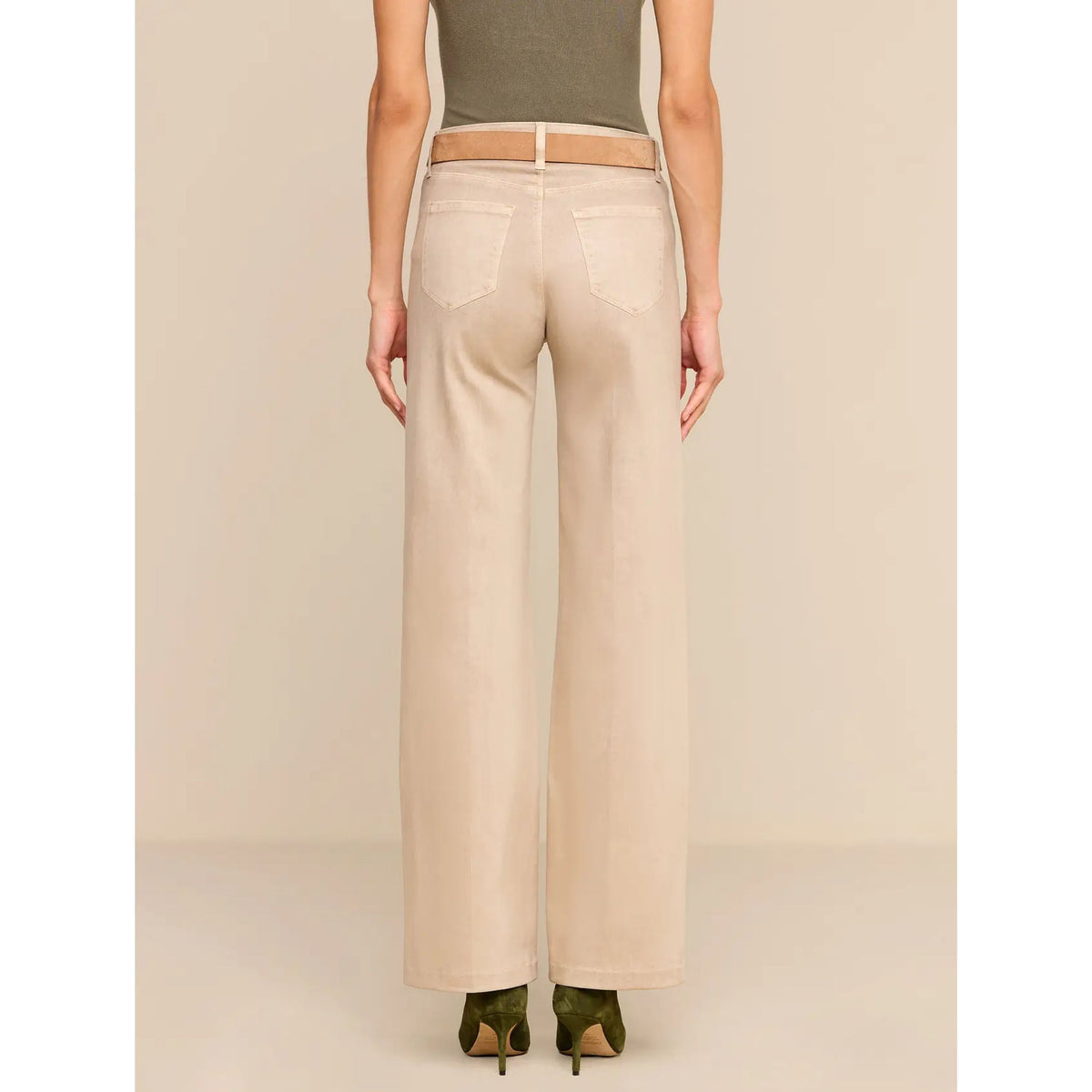A model shown from the back wearing light beige wide-leg jeans, a taupe belt, and olive green heels against a solid beige studio background.