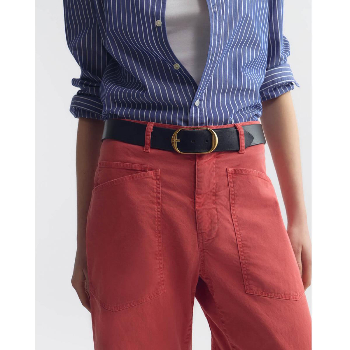 Person wearing a blue striped shirt, white top, red pants, and a black belt with a gold buckle on a white background.