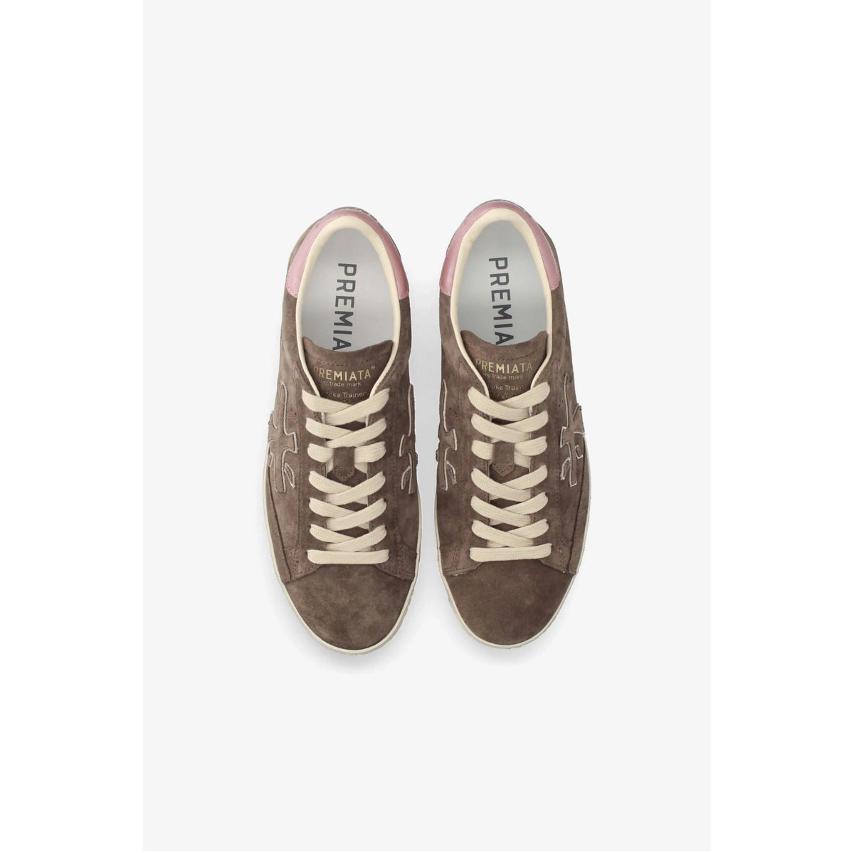 A pair of brown suede sneakers with cream laces and a light pink collar, shown from a top-down view on a light gray background. The brand name 'PREMIAS' is visible on the tongue.