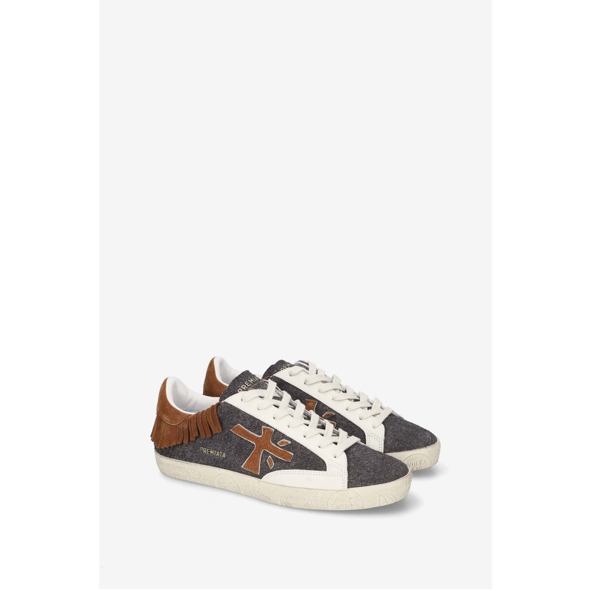 A pair of low-top sneakers in a textured dark gray fabric, featuring brown suede fringe on the heel, a brown cross-shaped logo on the side, and off-white laces and soles, shown against a light gray background.