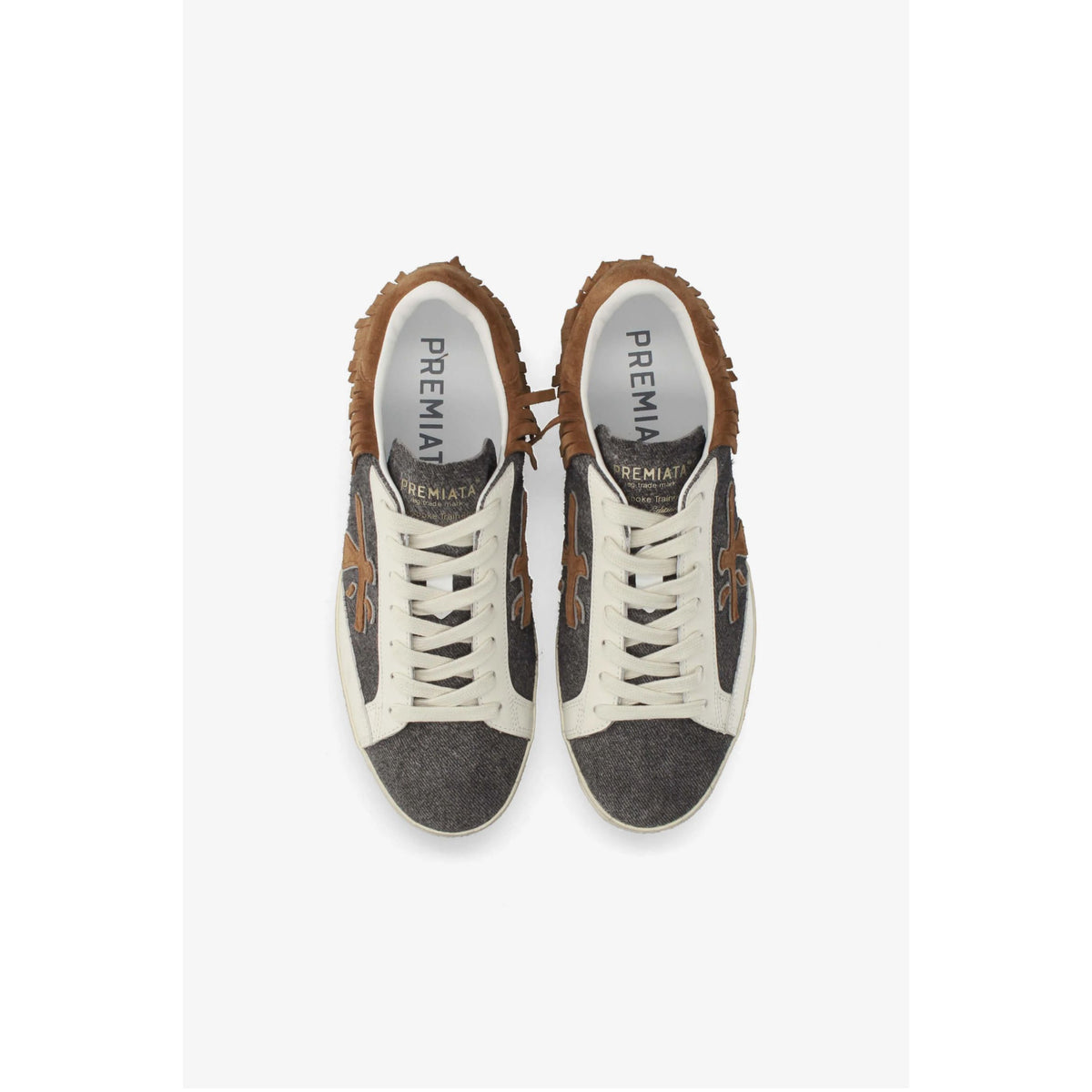 A pair of PREMIATA sneakers shown from a top-down view. The sneakers feature a dark gray textured fabric body, white laces, white side panels, and brown suede overlays with a frayed edge.