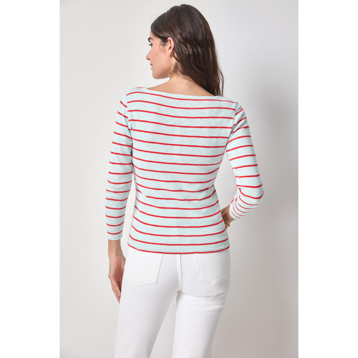 Woman wearing a red and white striped long-sleeve shirt and white pants on a light gray background