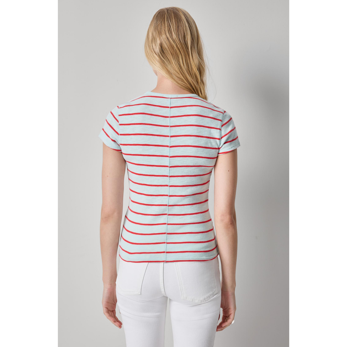 Woman wearing a striped shirt and white pants on a plain background