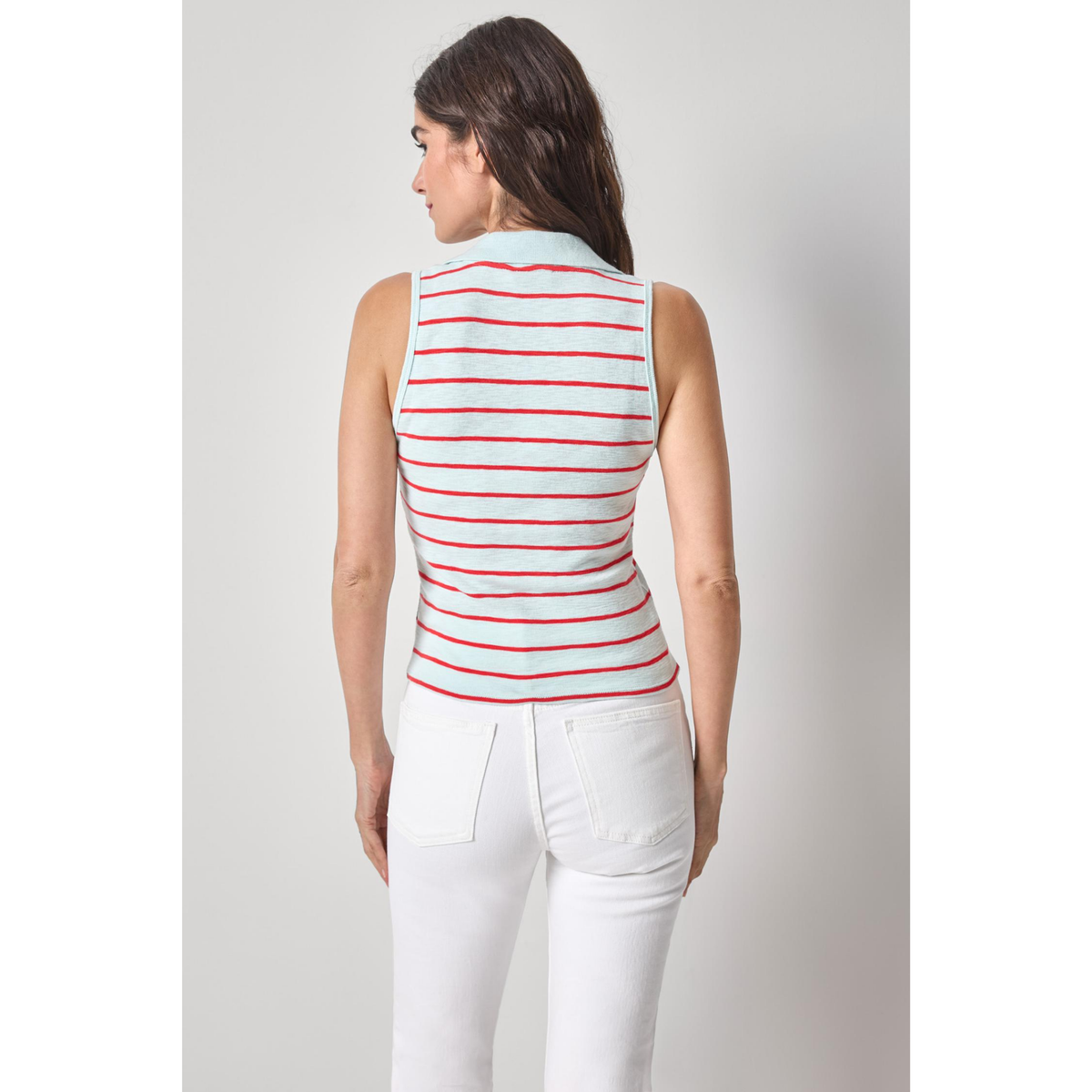 Woman wearing a red and white striped sleeveless top and white pants on a gray background