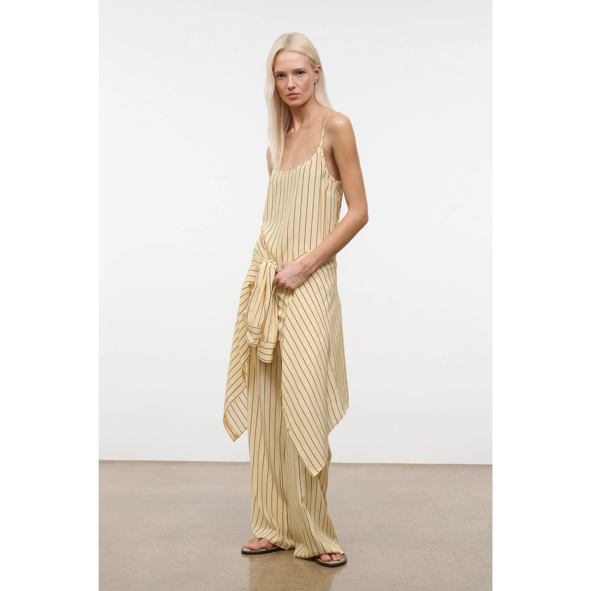 Woman wearing a beige ribbed dress against a white background