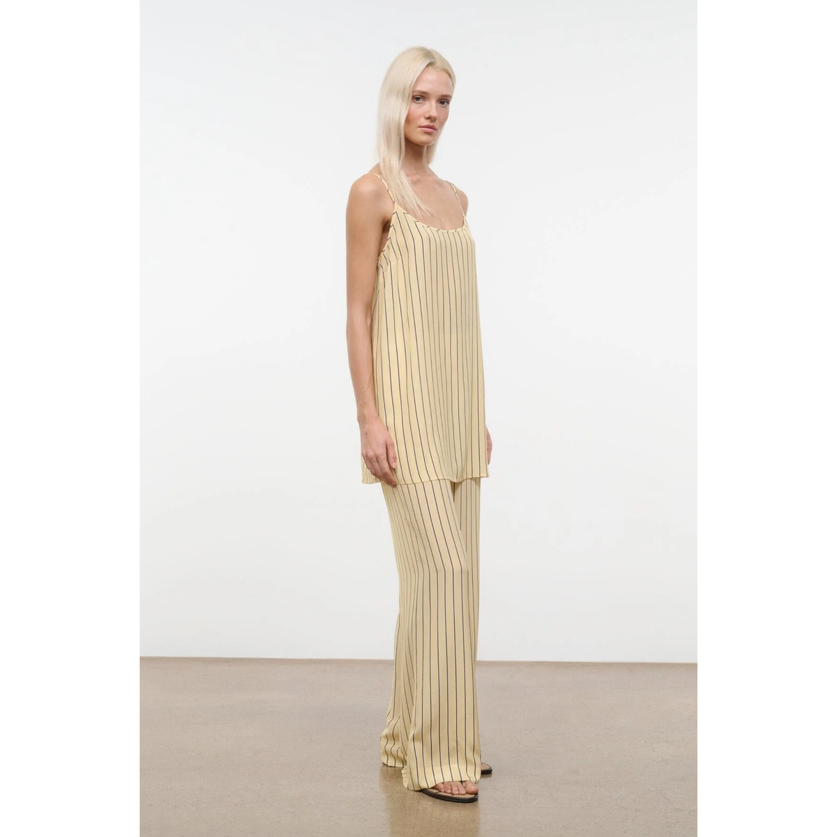 Woman wearing a beige pleated dress against a white background