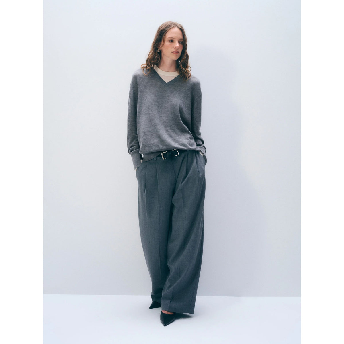 Full-length front view of a model wearing the grey v-neck layered sweater and matching wide-leg trousers.