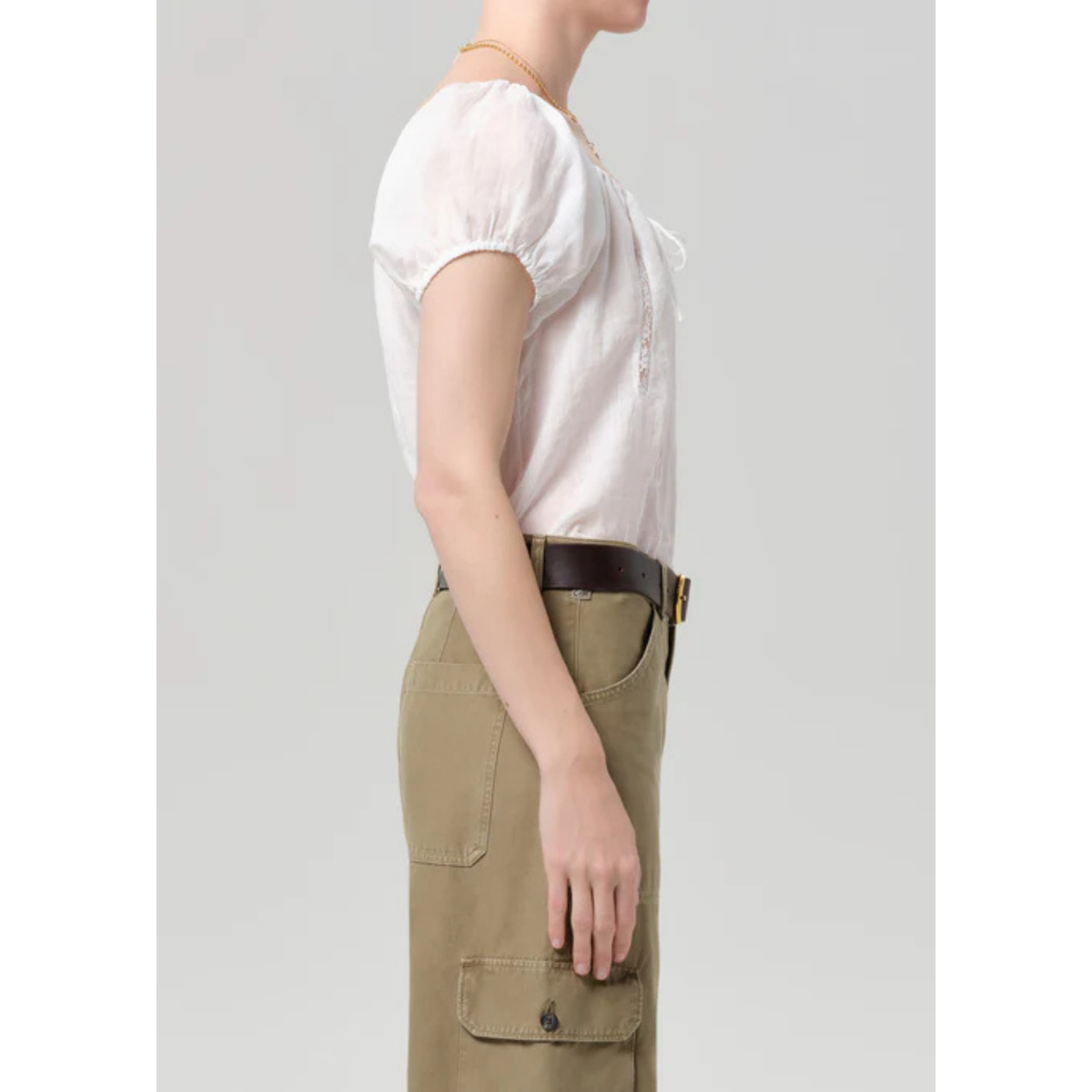 Person wearing a white blouse and beige cargo pants on a plain background