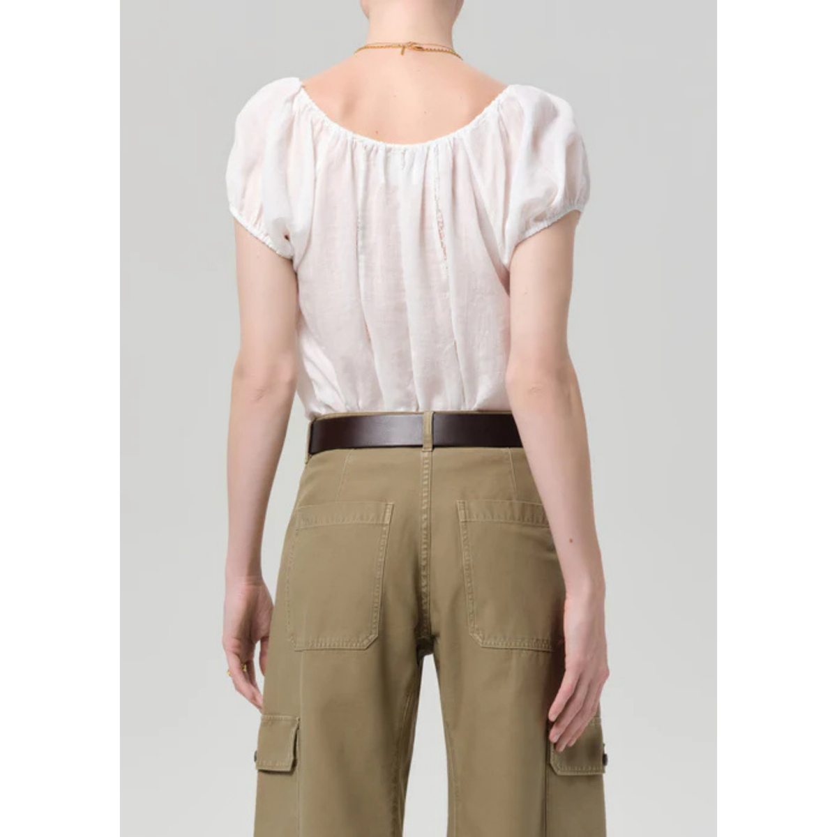 Person wearing a white blouse and khaki pants on a plain background