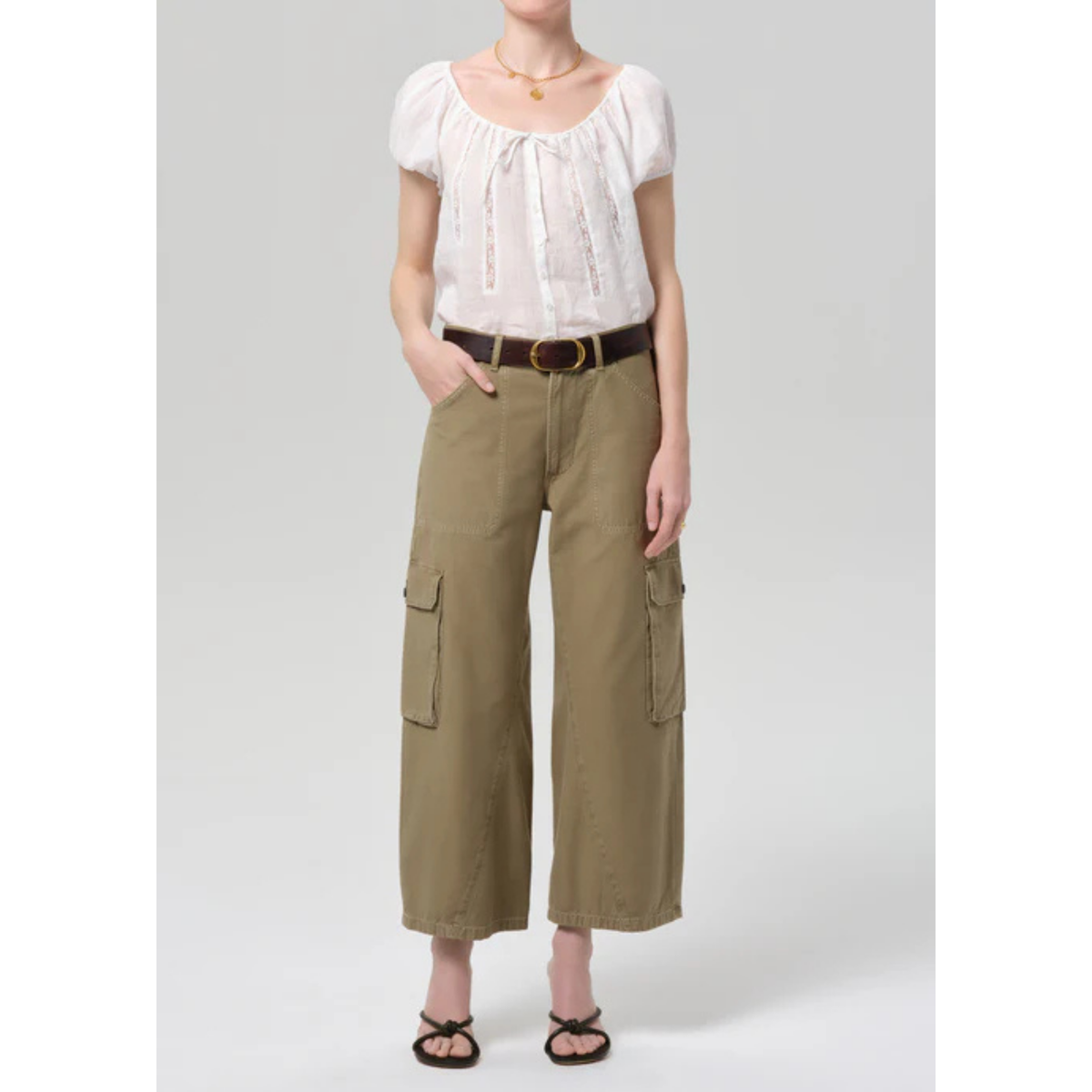 Person wearing a white blouse and beige cargo pants on a gray background
