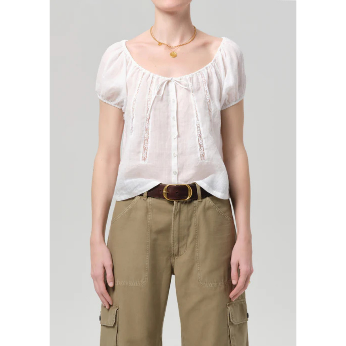 Person wearing a white blouse and beige pants on a gray background