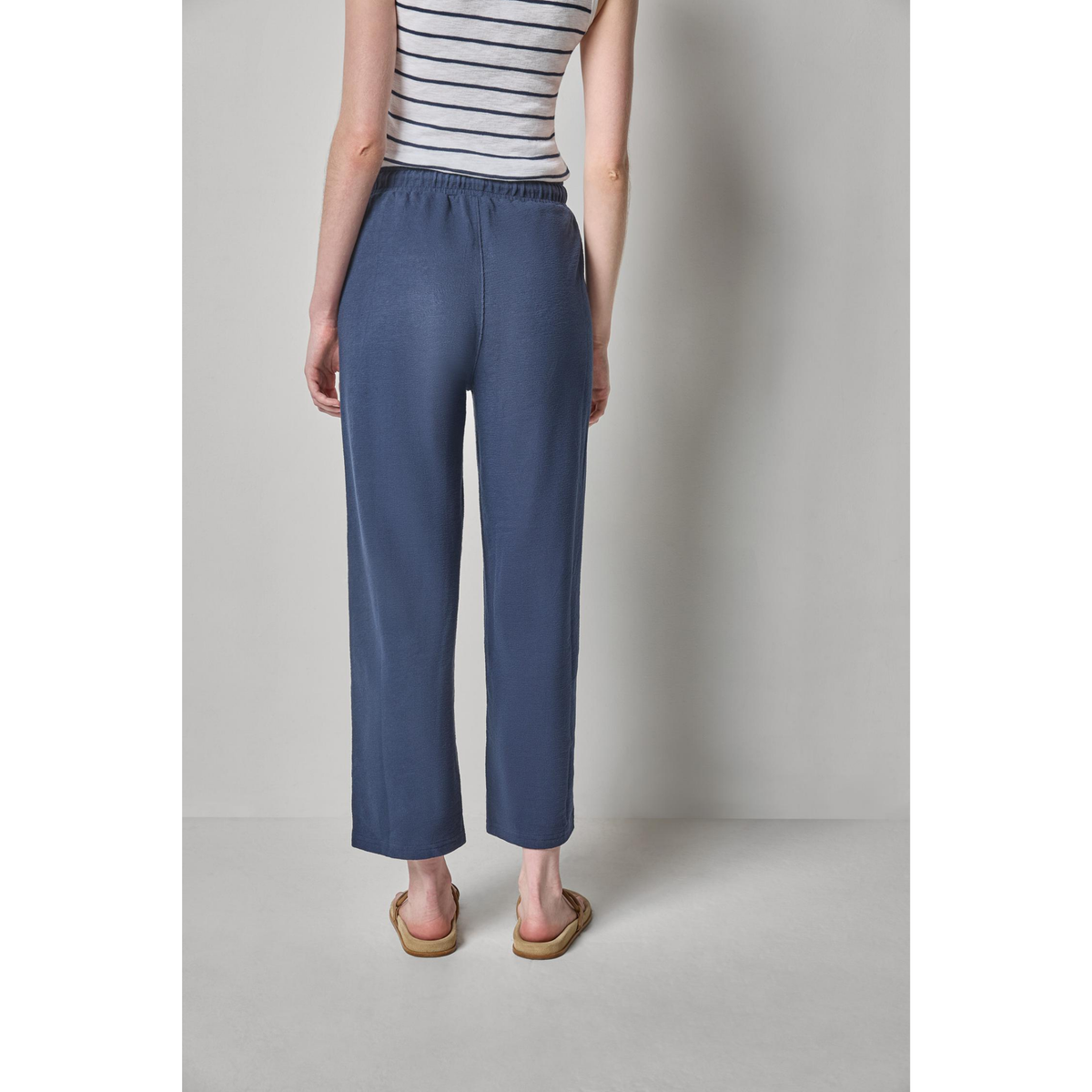 Person wearing blue pants and a striped shirt on a plain background