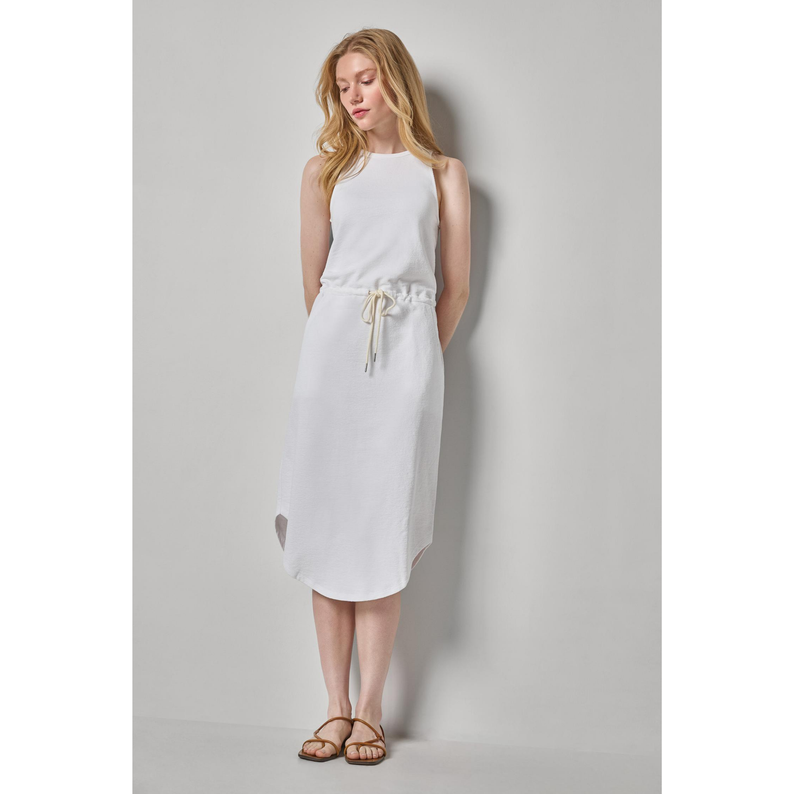 Two women wearing sleeveless dresses, one blue and one white, on a plain background.