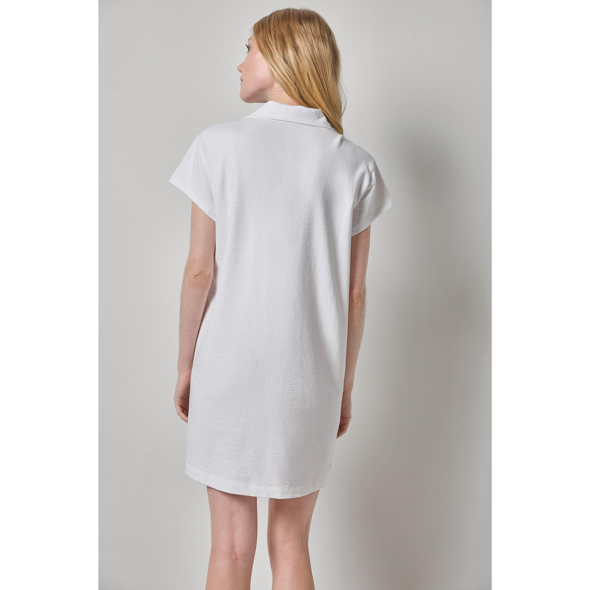 Woman wearing a white dress against a plain background