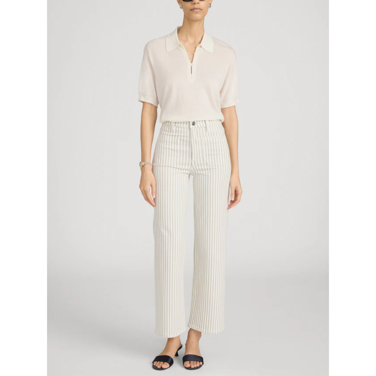 Woman wearing a beige blouse and striped pants on a white background