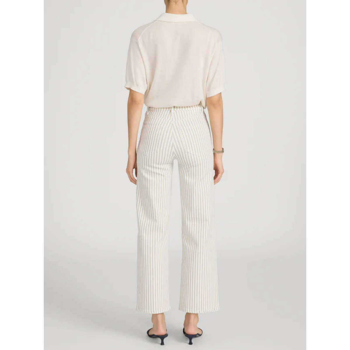 Person wearing a white blouse and striped pants on a plain background